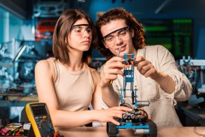 young man woman protective glasses doing experiments robotics laboratory robot